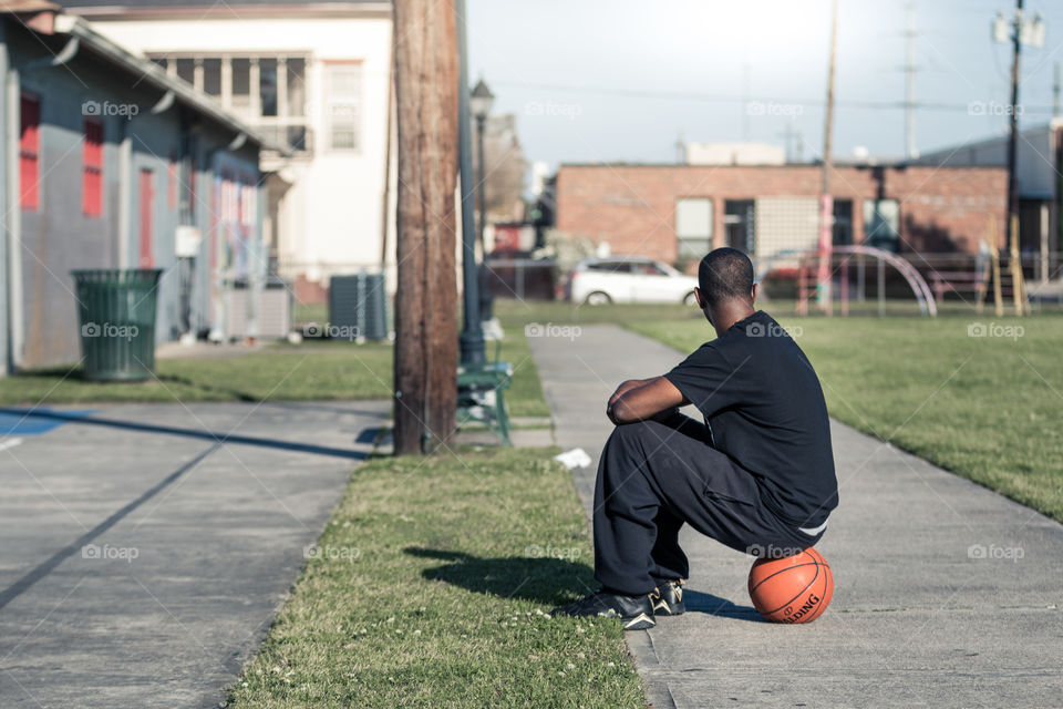 Man sitting on the basketball in the park