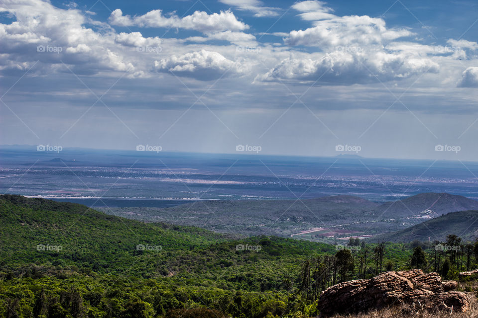 cloud cover over mountain with a big rock in the foreground