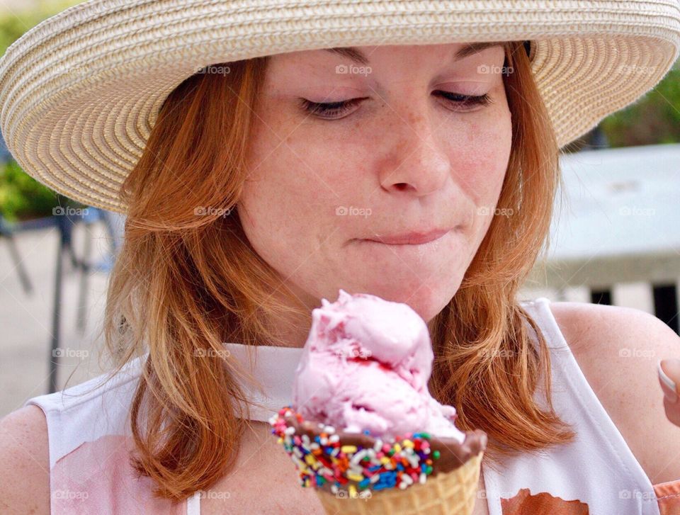 Pretty young woman enjoying a strawberry icecream with chocolate coating sprinkles!