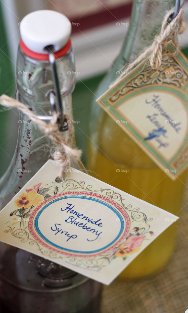 Bottles of homemade blueberry and lemon syrup in vintage bottles with handwritten tags
