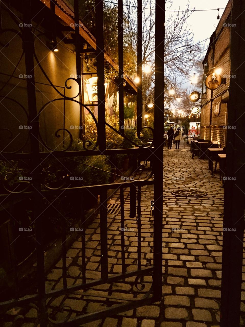 Passage through metallic door into cobblestones paved road in Providencia, Santiago, Chile by night 