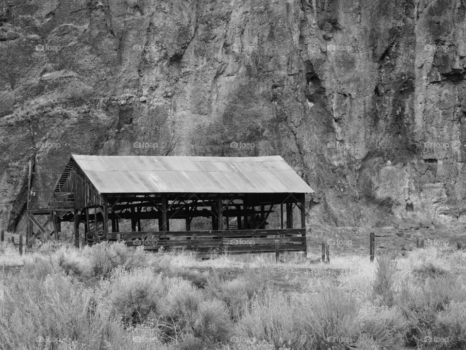 A cattle feed storage building at the base of a cliff in the rugged ranch lands of Eastern Oregon. 