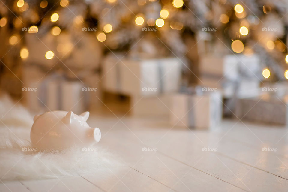 piggy bank with 100 dollars banknote in festive New Year atmosphere of scenery.  Magical bokeh with Christmas tree and bright lights.