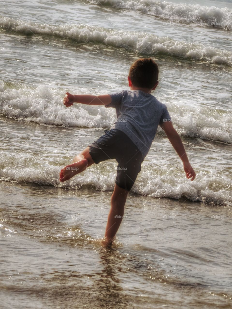 Little boy dancing in the ocean.