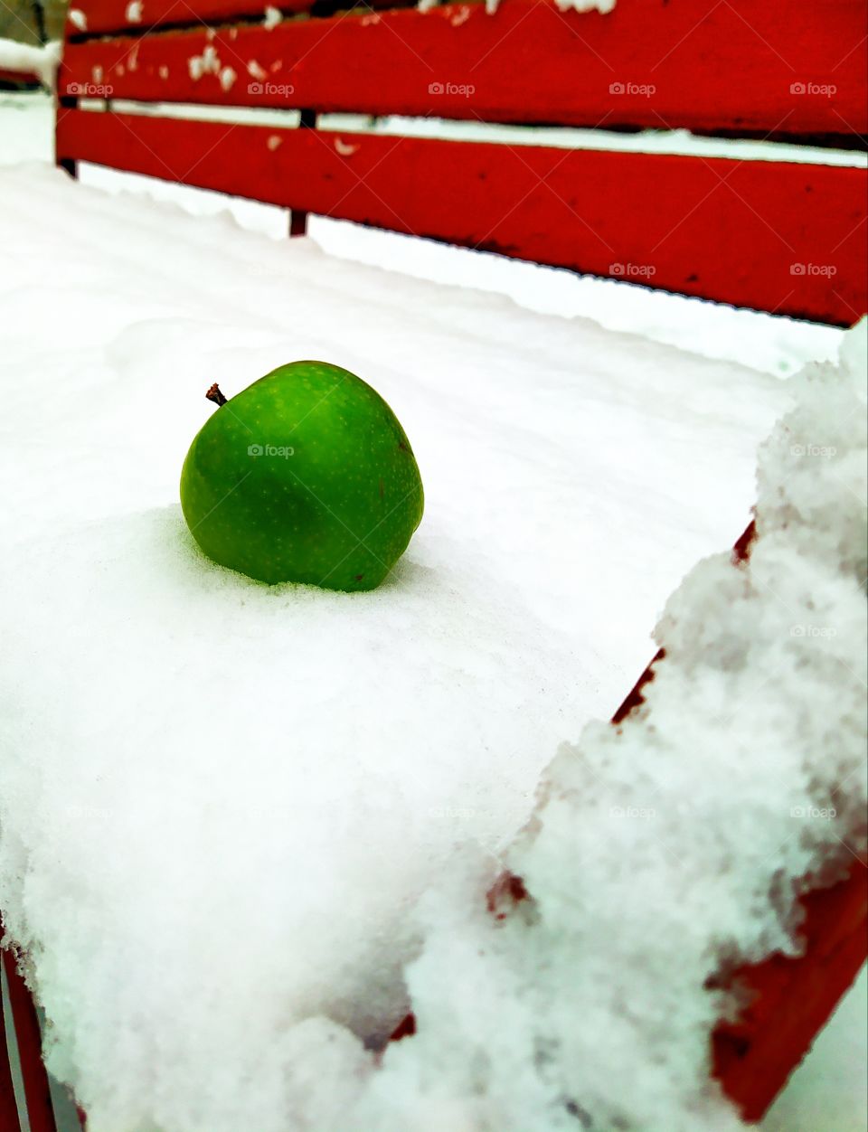 Green apple on a snow-covered bench
