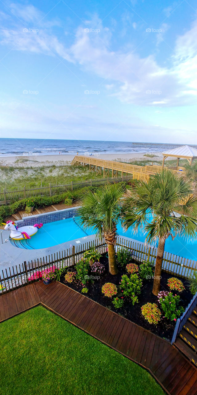 overlooking an oceanfront pool and garden with gazebo and oversized unicorn float.