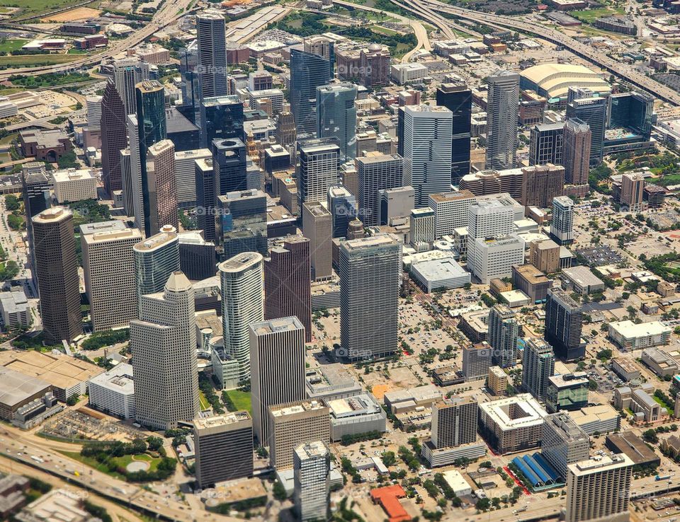 A modern city seen from the air features a multitude of tall buildings creating a rectangular skyline