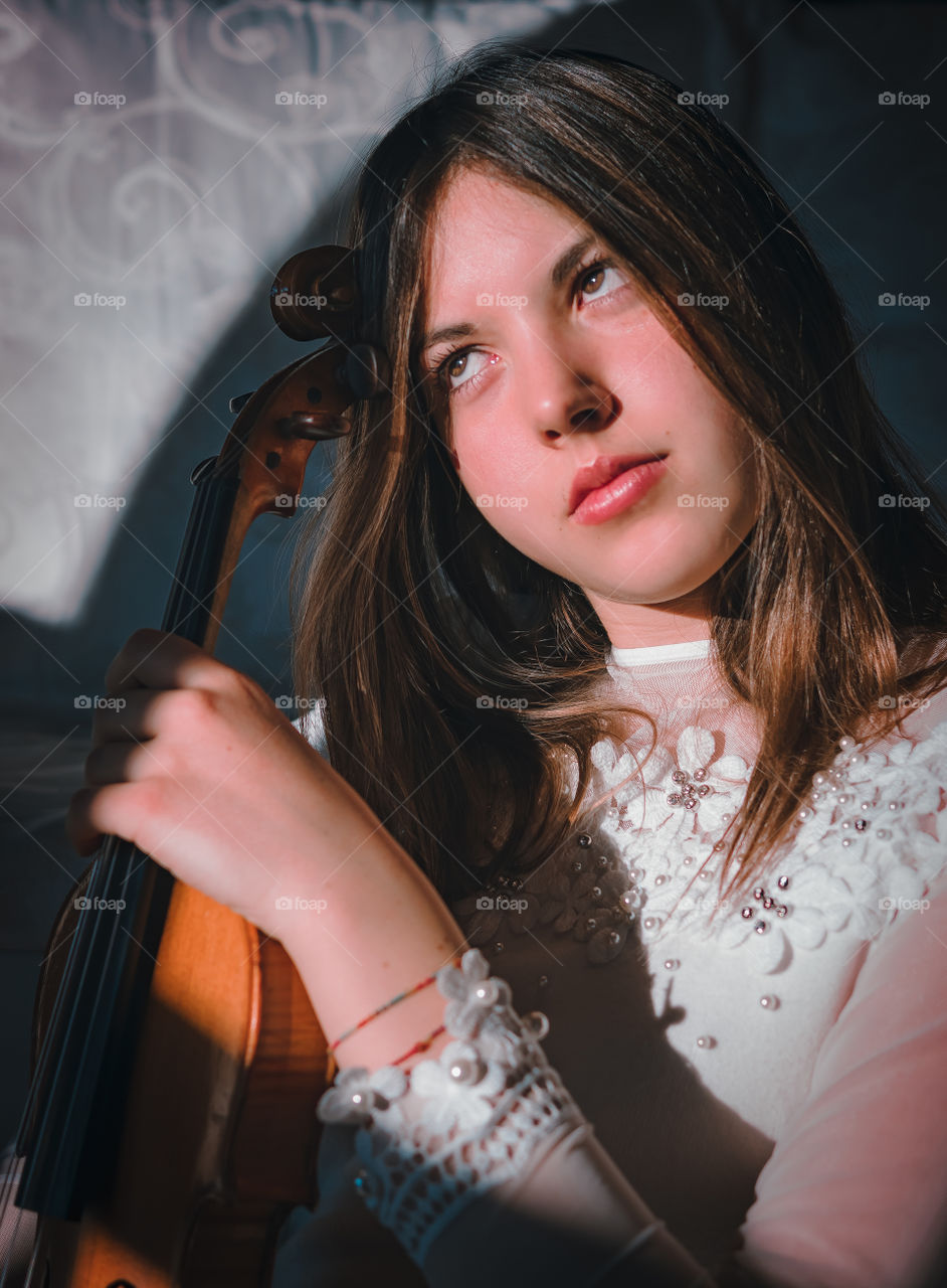 Girl holding a violin in the house