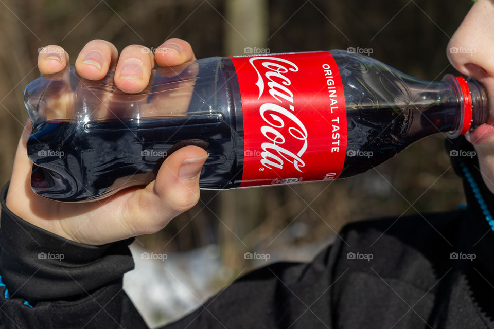boy drinks a bottle of Coca Cola