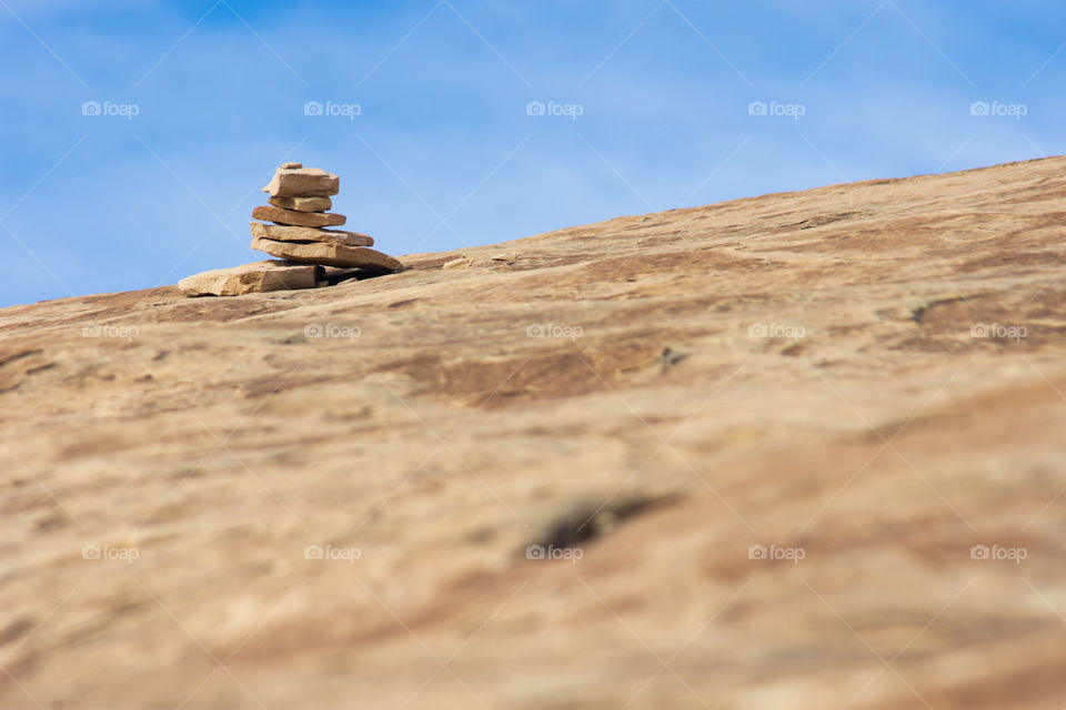 A cairn marks the trail on a slickrock surface.  Set against the sky.