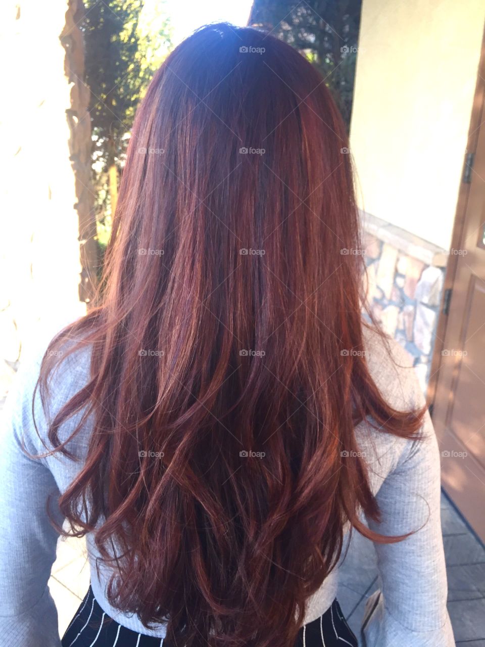 The back of a young woman’s head with reddish brown balayage ombré hair
