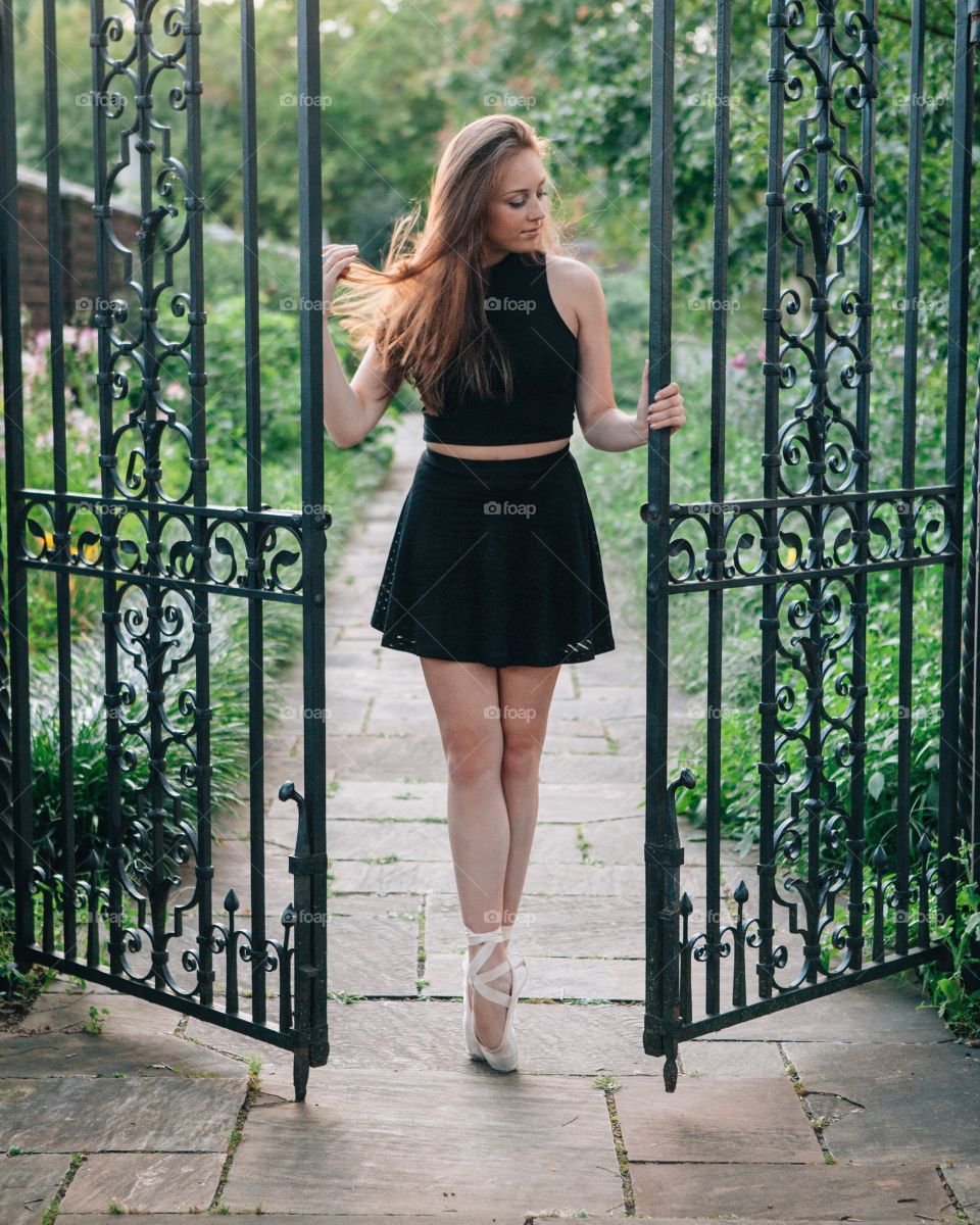 Ballerina stands at open gate.
