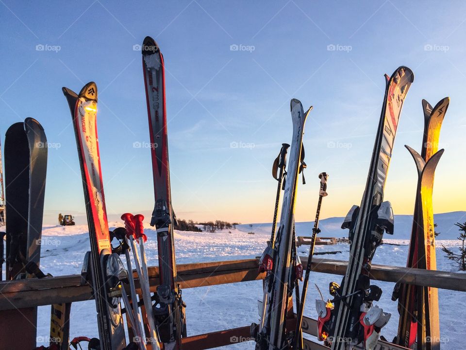 Group of skis gathered together at sunset