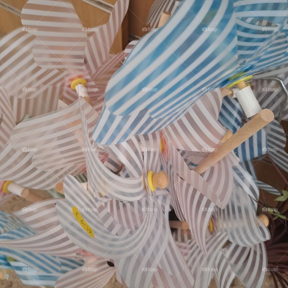 pink and blue striped toy windmills in a cluster in a shop childrens