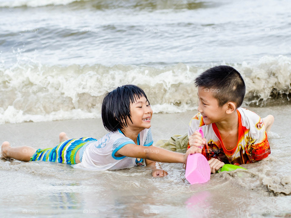 Happy Asian children playing on the beach.