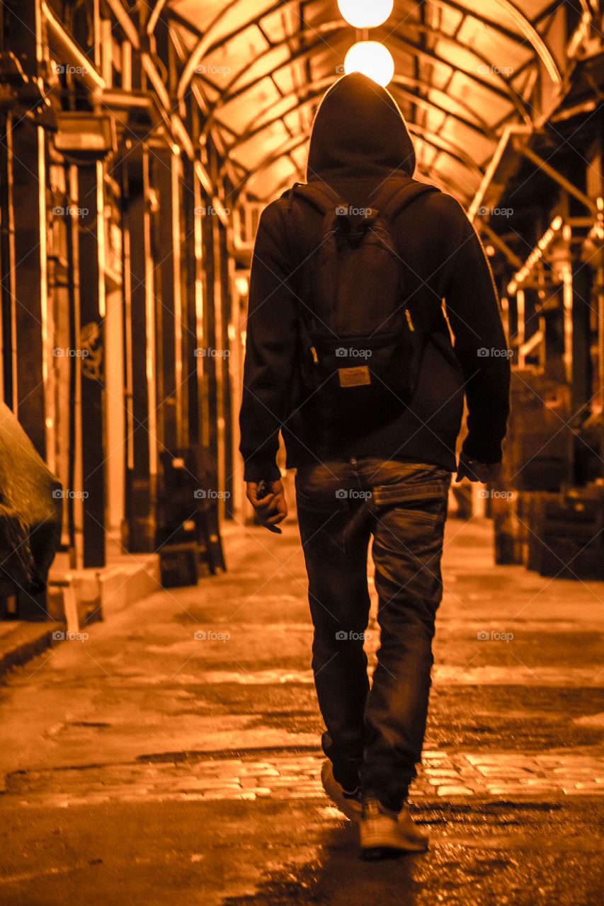 Young Man Walking On An Arcade At Night
