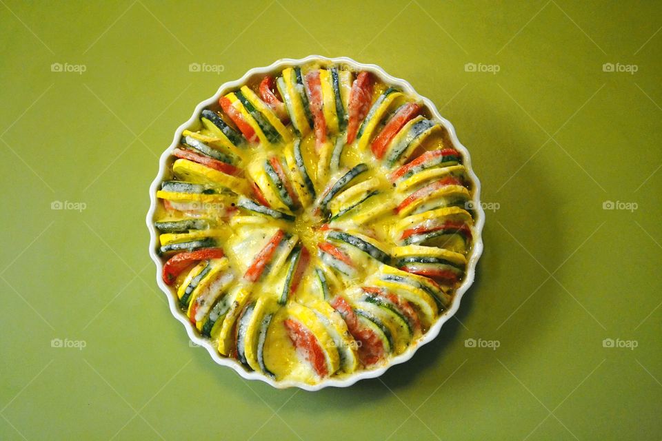 Round vegetable tian of colorful zucchini, yellow squash, tomatoes and onions in bubbling cheese sauce