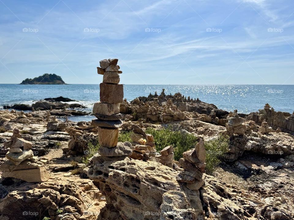 Stacked rock cairns on a rocky beach in summer 