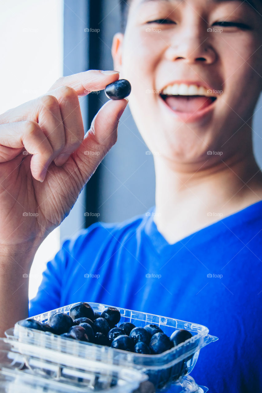 Young man picking and holding fresh organic blueberries 