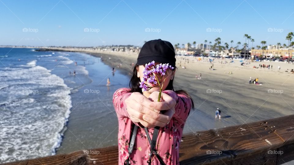 woman holding a flower facing front the camera at the beach pier