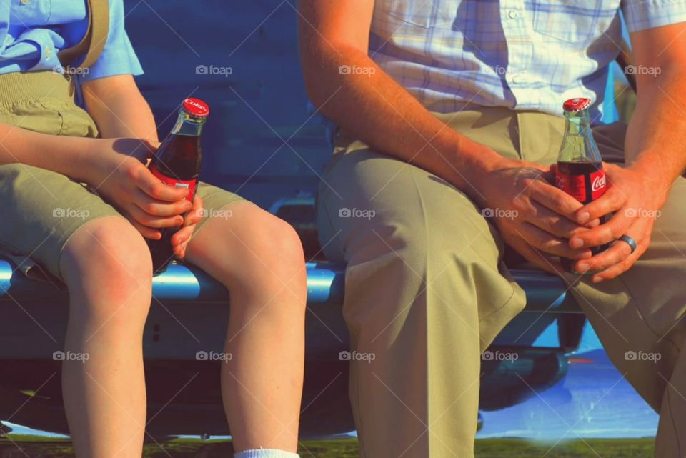 Enjoying a coke. A father and son sitting on the back of a tailgate enjoying a coke