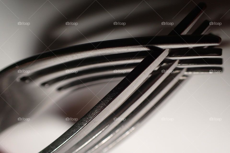 Closeup interlocking silver forks with shadows