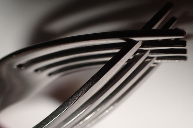 Closeup interlocking silver forks with shadows