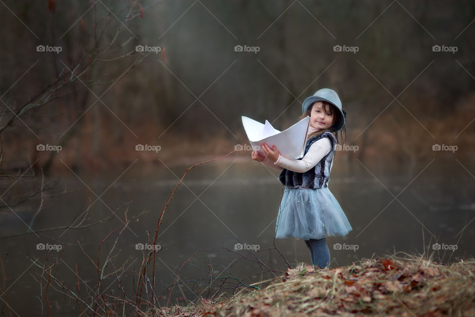 Little girl with paper boats at spring river