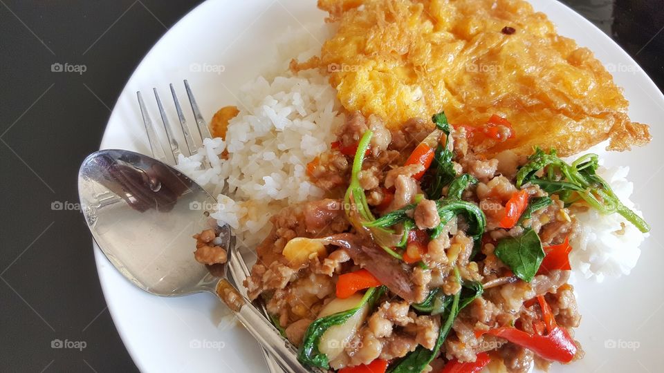 Steamed rice topped with stir-fried pork and basil, fried egg