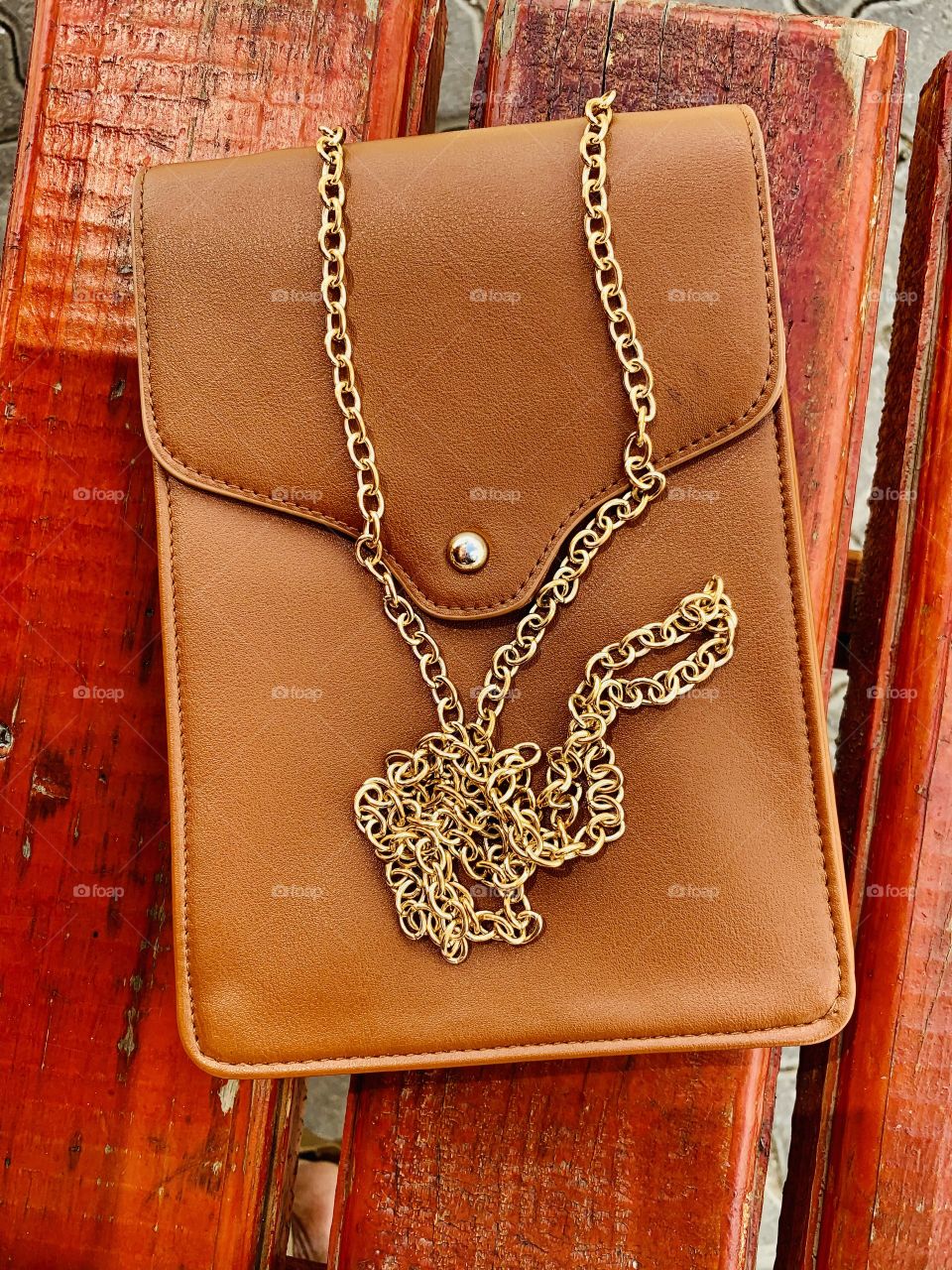 A beautiful and brown ladies’ purse. It has along golden chain for a handle. 