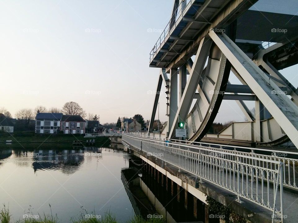 In the foreground, Pegasus Bridge was the site of some of the first actions of the Normandy landings. In the background, the first houses liberated in France in June 1944.