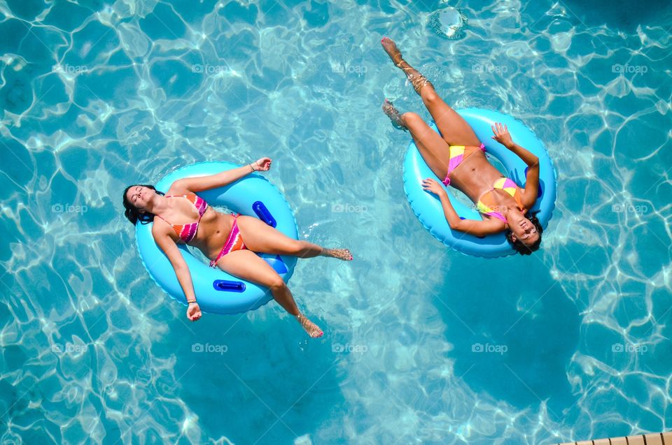 Two girls relaxing in a swimming pool.