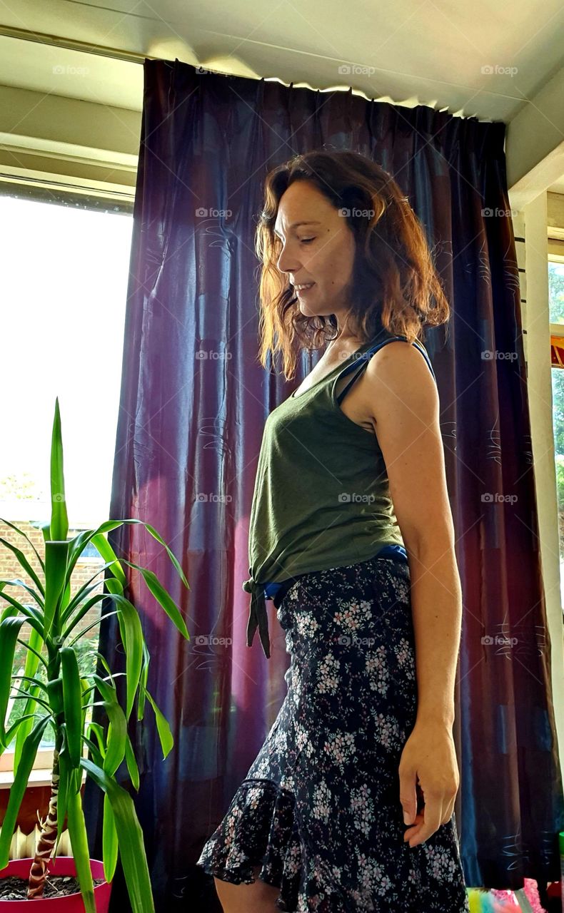 In the living room, a woman with a small smile.