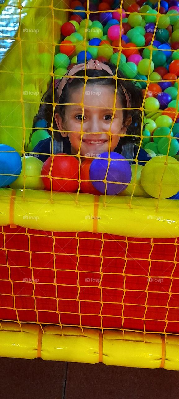 niña sonriente jugando en parque de bolas
