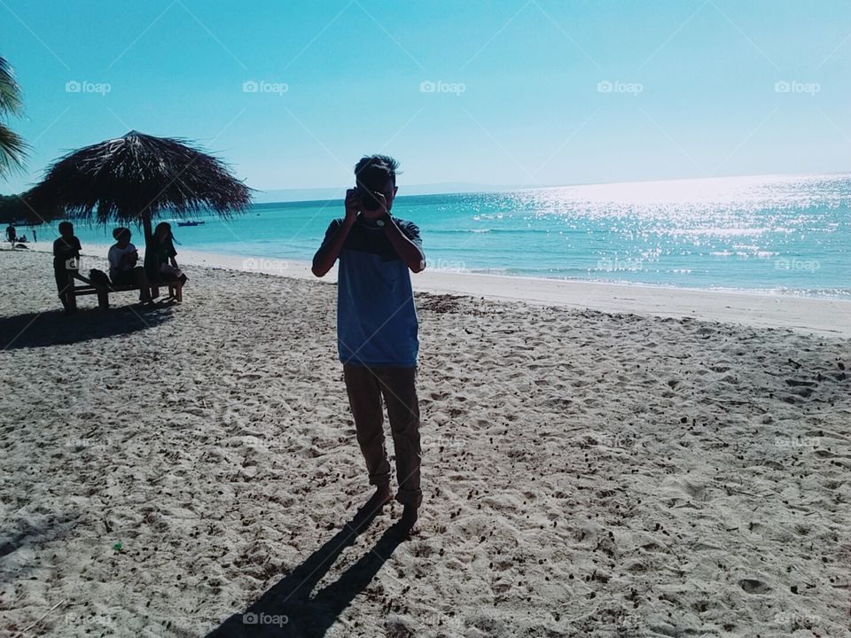 Shadow of the sun on the sea, shadow of the photographer and shadow of the parasol reeds