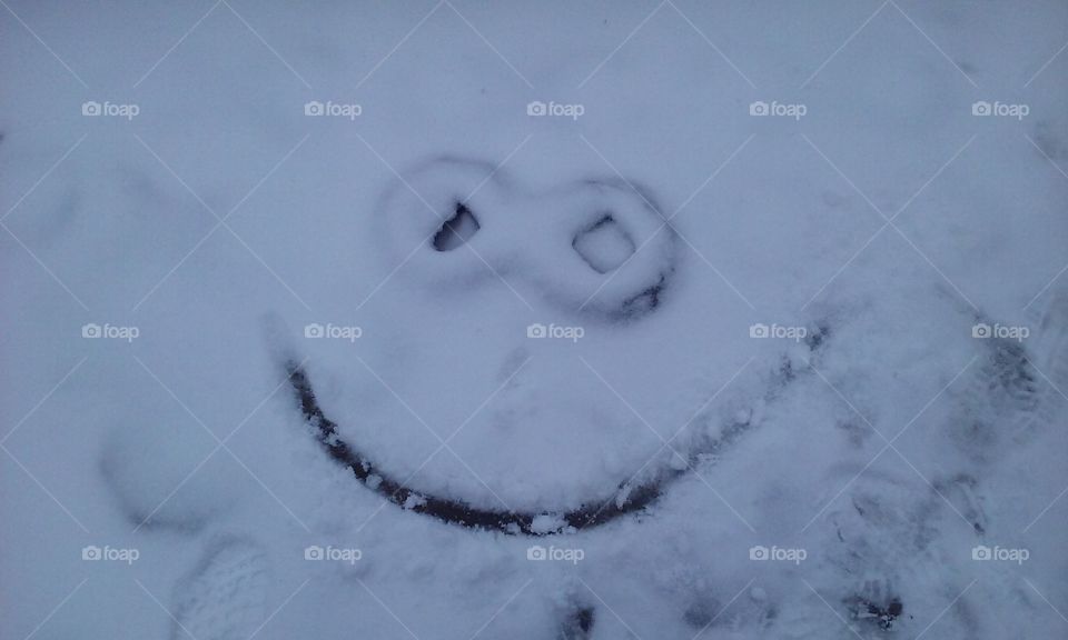 a smile in the snow made by a manhole cover