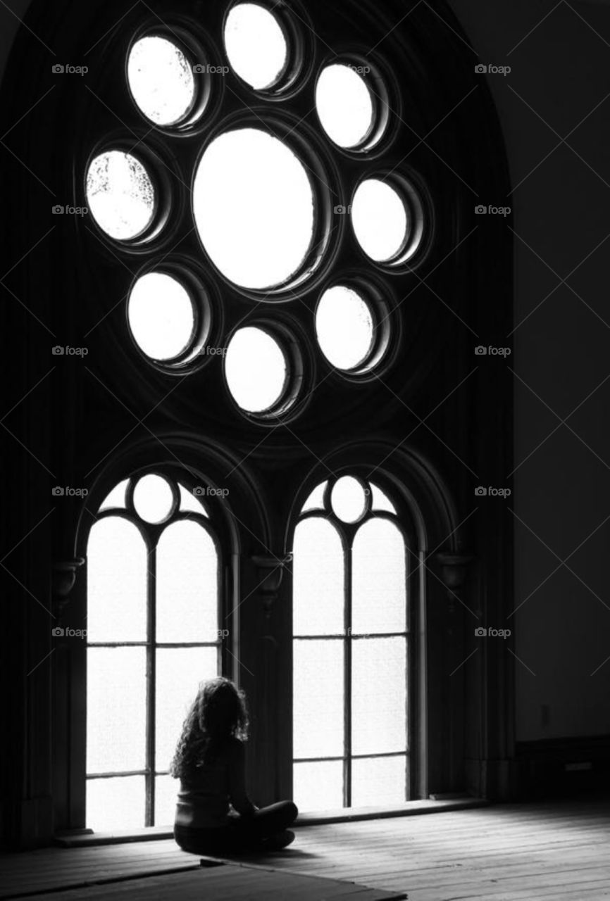 Girl sitting in front of large windows 