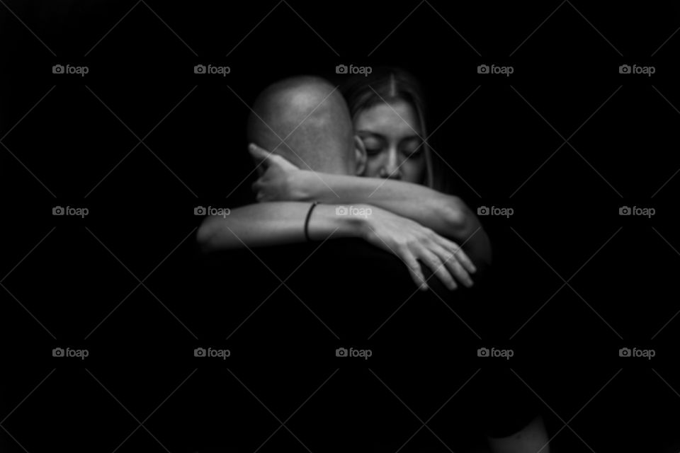 Couple hugging against black background