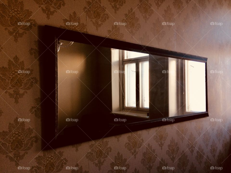 A mirror on a patterned wall with a view to Windows 